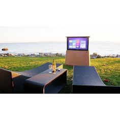 an outdoor seating area with a television on the wall and table in front of it