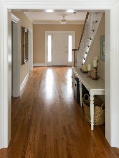 an open door leading to a hallway with wooden floors and white trim on the walls