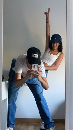 a man and woman standing in front of a white wall with their arms up to each other