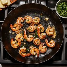 shrimp being cooked in a skillet on top of an oven with garlic and parsley