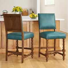 two wooden chairs with blue leather upholstered backrests in front of a kitchen island