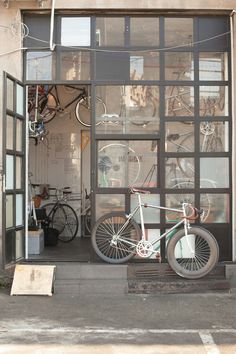 a bicycle is parked in the window of a bike shop with its front door open