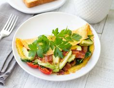 an omelet with bacon, avocado and cilantro on top