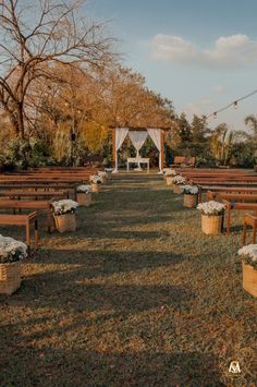 an outdoor wedding setup with wooden benches and white drapes on the top of them