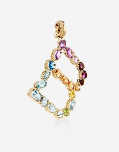 The yellow gold charm is illuminated by a veritable rainbow of natural gemstones such as topaz, garnet, amethyst, citrine, peridot and tourmaline. the shades of their colours, dominated by blue, green, purple, red, pink and yellow, evoke the warm atmospheres of Sicily. The multiple shapes of the crystals are also emphasized by the bezels, which alternate twisted thread processing and smooth surfaces. Technical specifications. Gold yellow 18 Kt. Gemstones. n.1 oval deep purple amethyst, n.1 cushion purple amethyst, n.1 drop shaped light purple amethyst, n.1 oval very light purple amethyst, n.1 round pink tourmaline, n.1 oval cabochon red violet rhodolite garnet, n.1 oval orange-red exonite garnet, n.1 oval “Madeira” quartz, n.1 round intense yellow citrine, n.1 oval yellow citrine, n.1 oval Rainbow Alphabet, Red Violet, Yellow Citrine, Rhodolite Garnet, Gold Fashion, Oval Cabochon, Gold Charm, Pink Tourmaline, Gold Yellow