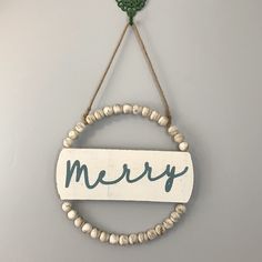 a sign that says merry hanging on a wall with beads and a wooden bead