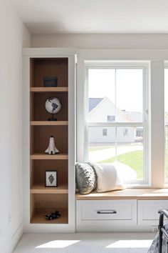 a window seat in the corner of a room with bookshelves and pillows on it