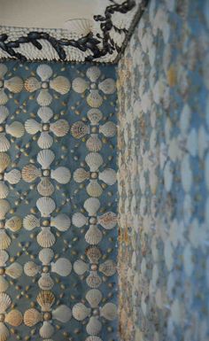 the wall paper has shells on it and is blue with gold dots, along with black trim