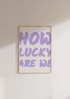 a purple and white poster that says how lucky are we on the wall above a bed