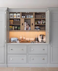 an organized kitchen with gray cabinets and white counter tops, along with coffee maker on the far wall