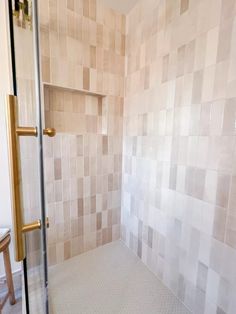 a walk in shower sitting inside of a bathroom next to a wooden table and chair