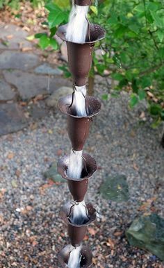 a wind chime hanging from the side of a tree in front of some bushes