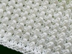 a close up view of a white crocheted blanket on a green tablecloth