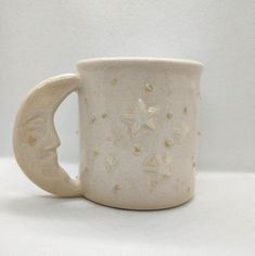 a ceramic coffee cup with stars and moon designs on the outside, sitting on a white surface