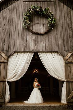 a bride standing in the doorway of a barn