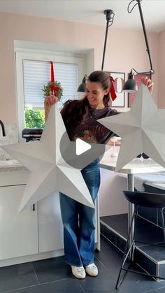 a woman standing in front of a white star hanging from a kitchen ceiling over a sink