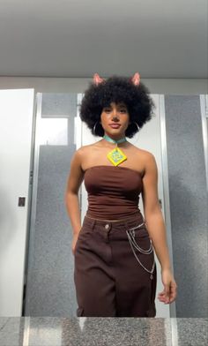 a woman with an afro standing in front of a mirror wearing a brown top and pants