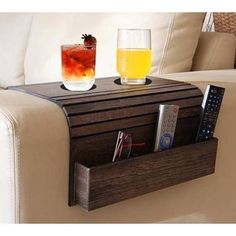 two drinks are sitting on a wooden shelf next to a remote control and cup holder