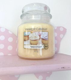 yankee candle vanilla cupcakes on pink shelf next to polka dot wallpaper with white polka dots