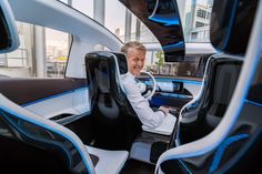 a man sitting in the driver's seat of a futuristic car with blue accents