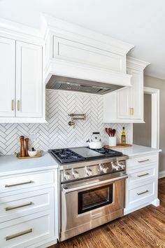 a kitchen with white cabinets and stainless steel stove top oven in the center is instagram