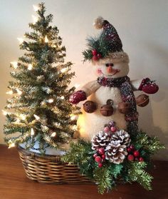 a snowman and christmas tree in a basket on a table with lights around it