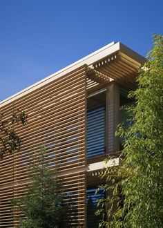 an exterior view of a house with wooden slats on the side and trees in front