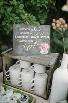 a table topped with lots of white cups and vases next to a wooden box