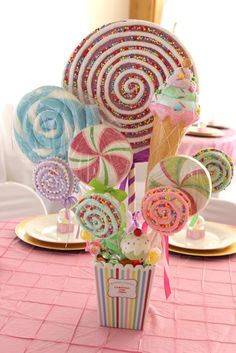 a table topped with lots of candy and lollipops on top of plates