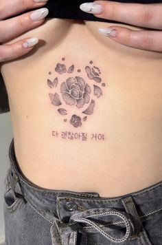 a woman's stomach with a rose tattoo on her side and words written in korean