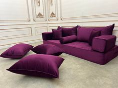 a purple couch and two pillows on the floor