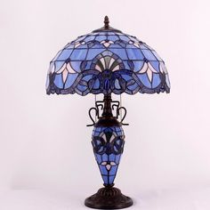 a table lamp with a blue glass shade on the top and an ornate iron base