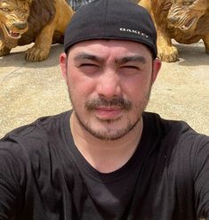 a man is taking a selfie in front of statues of lions on the ground