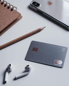 a credit card sitting on top of a table next to ear buds and an iphone