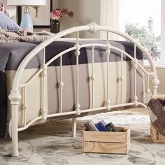 a white metal bed frame in a bedroom with a basket on the floor next to it