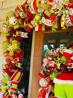 a christmas wreath is hanging on the front door with santa's stockings and candy canes