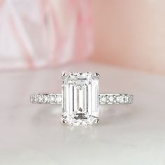 an emerald - cut diamond ring sits on a table