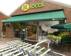 a grocery store with lots of carts parked in front of it and green awnings