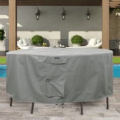 an outdoor table covered with a cover next to a swimming pool