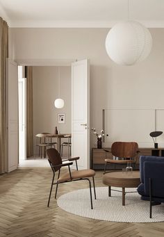 a living room filled with furniture next to a white wall and wooden floored walls