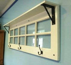 an old window is hung on the wall with black hooks and two coats of coat hangers