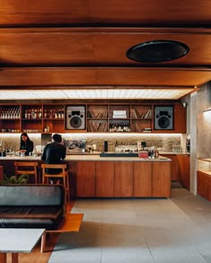 two people sitting at a bar in a room with wood paneling on the walls