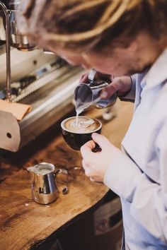 a woman pours coffee into a glass in front of an espresso machine