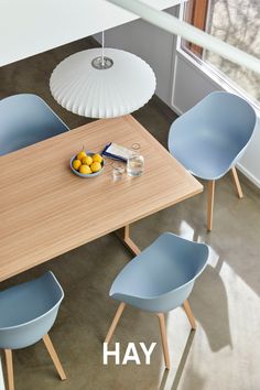 a wooden table topped with blue chairs next to a bowl of lemons and an umbrella