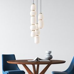 a dining room table with blue chairs and a white vase hanging from it's ceiling