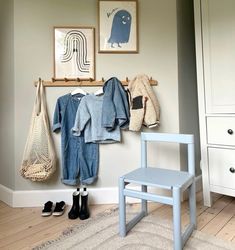 a blue chair sitting in front of a wall with clothes hanging on it's hooks