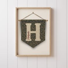 a wooden frame hanging on the wall with a sign that says h and has flowers in it