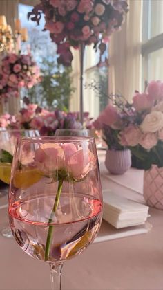 a wine glass filled with pink flowers on top of a table