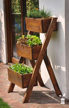 three wooden planters with plants in them sitting on the side of a building next to a door