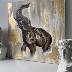 an elephant painted on a canvas next to a white busturine and gold leafed wall